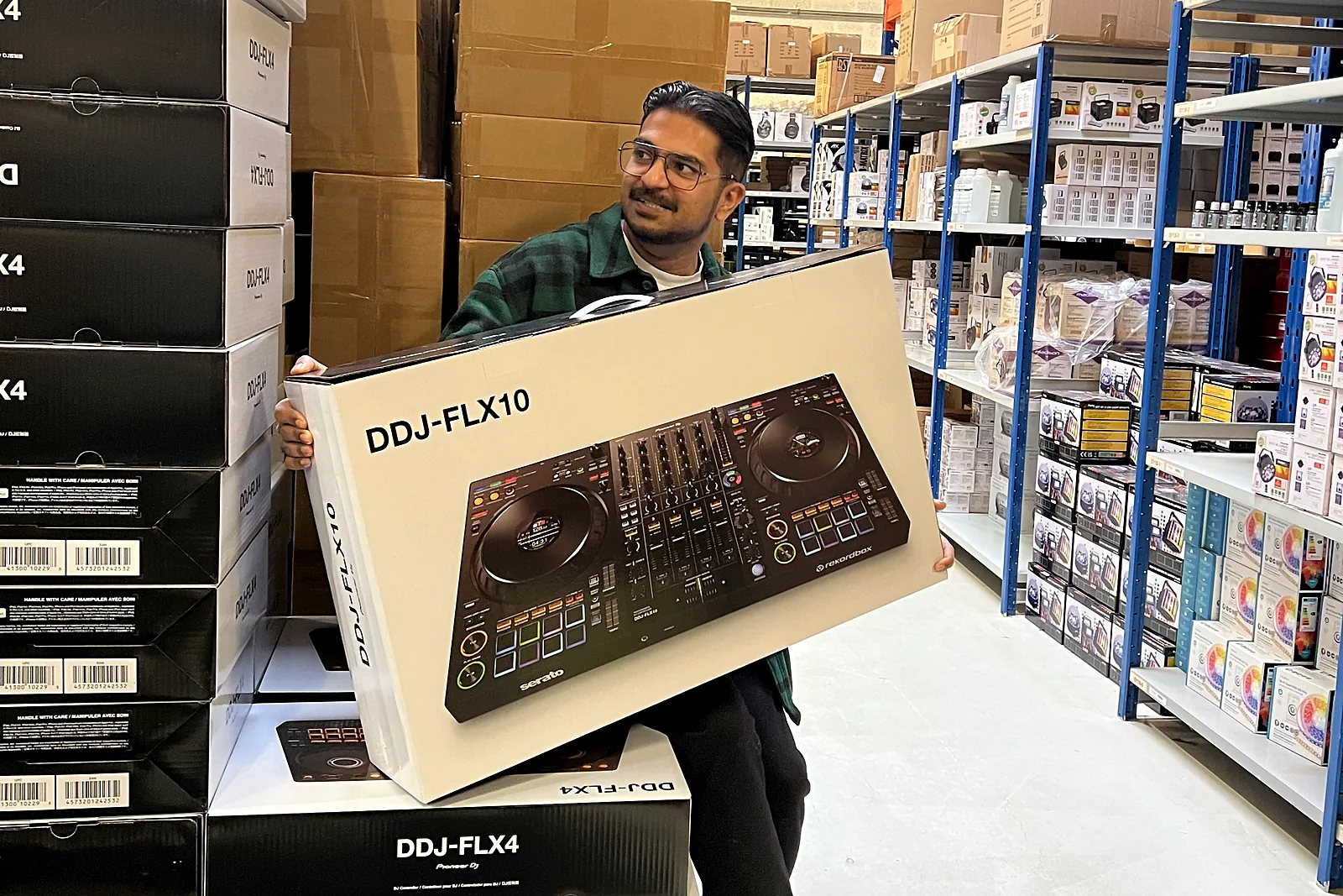 Rasmus holder en DDJ-FLX10 i kassen mellem stakke af DJ-controllere