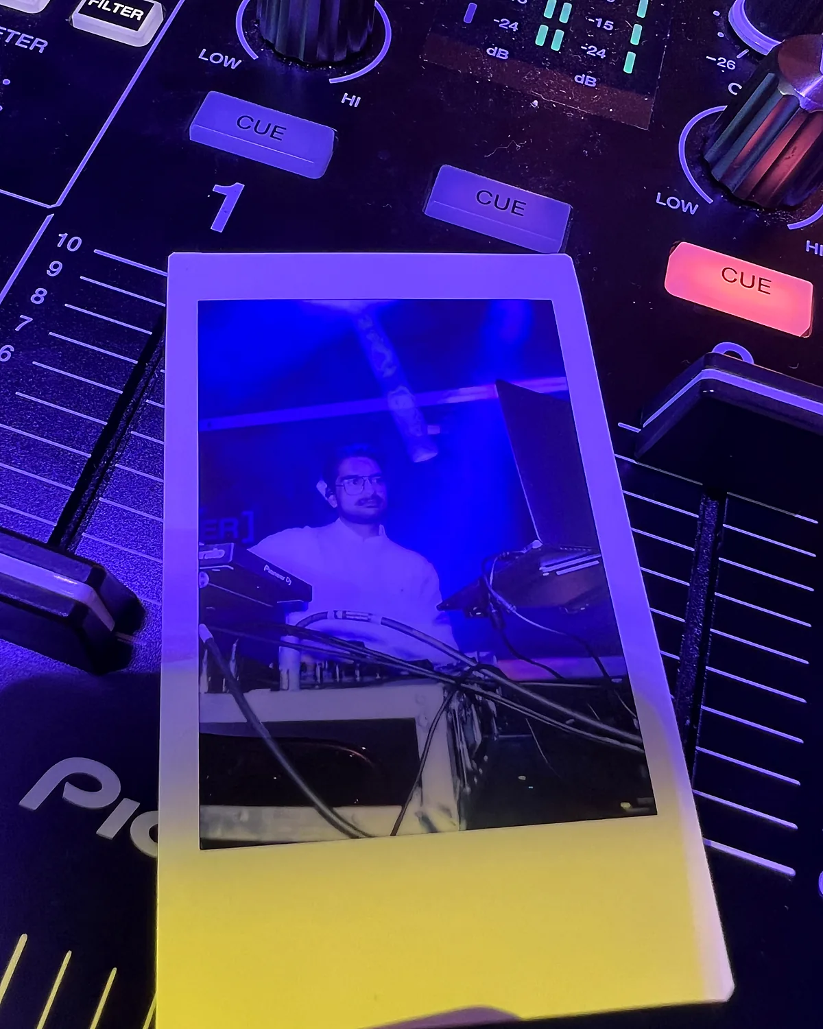 Et polaroidbillede af Rasmus bag pulten, lagt på en DJ-mixer
